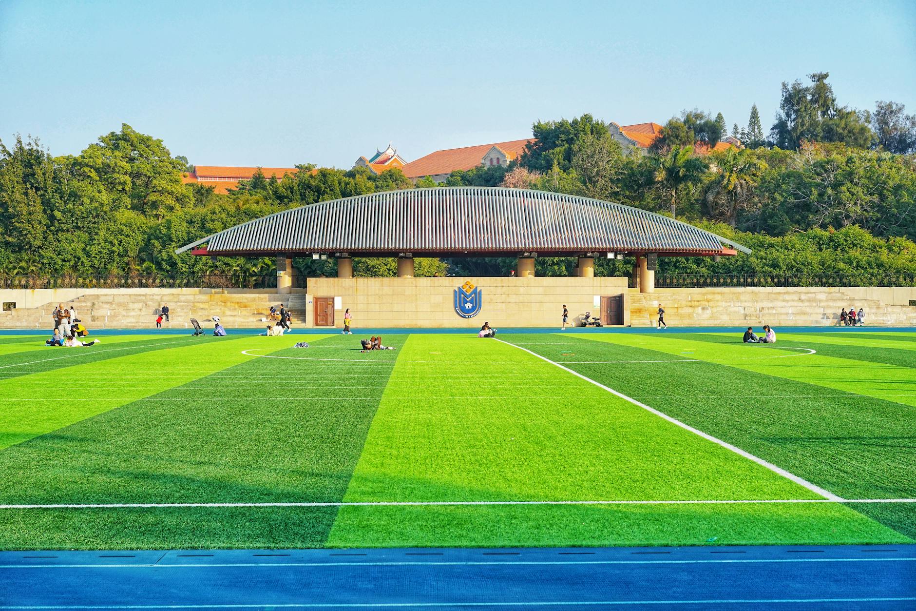 Studenci odpoczywający na jasnym boisku sportowym pod błękitnym niebem