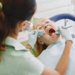 Dentystka bada zęby pacjenta w gabinecie stomatologicznym