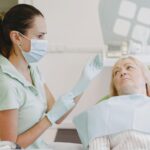 Dentystka przygotowuje starszą pacjentkę do badania stomatologicznego