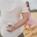 Mężczyzna z pierścionkiem zaręczynowym za plecami na plaży