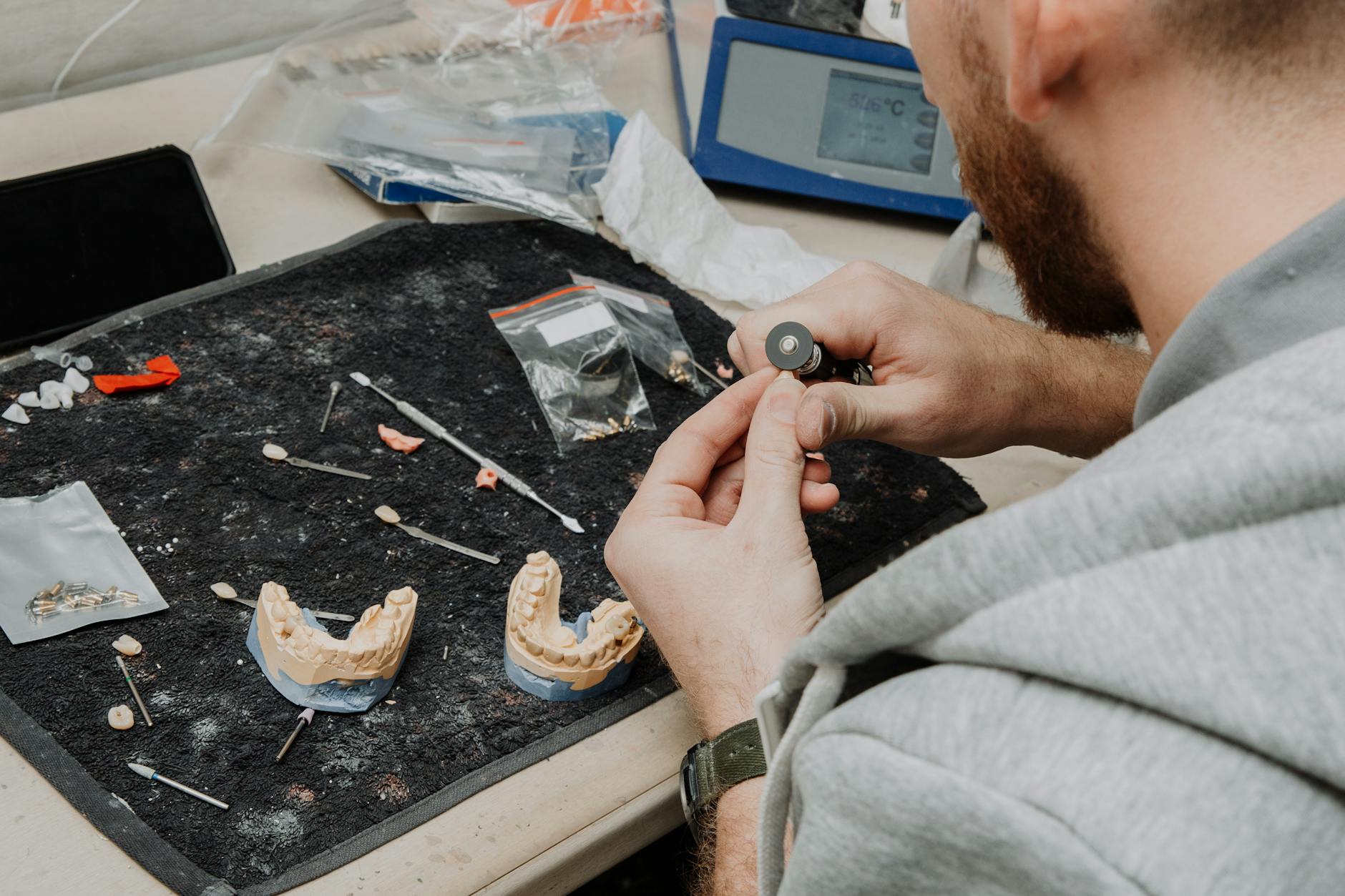 Technik dentystyczny obrabia wycisk szczęki przy stole w pracowni