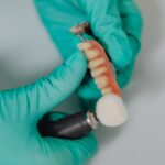 Dentysta precyzyjnie poleruje protezę na implantach zębowych