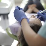 Dentysta w rękawiczkach leczy ząb pacjenta w nowoczesnym gabinecie