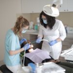 Dentystka w masce leczy zęby pacjentce w nowoczesnym gabinecie