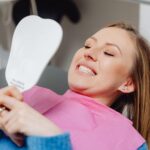 Pacjentka w klinice stomatologicznej ogląda efekt leczenia w lusterku