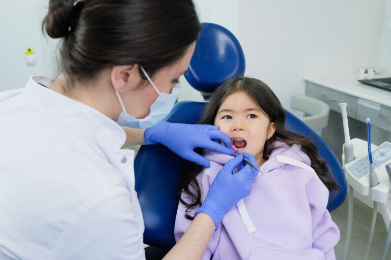 Dentystka bada zęby dziewczynki podczas wizyty w gabinecie stomatologicznym